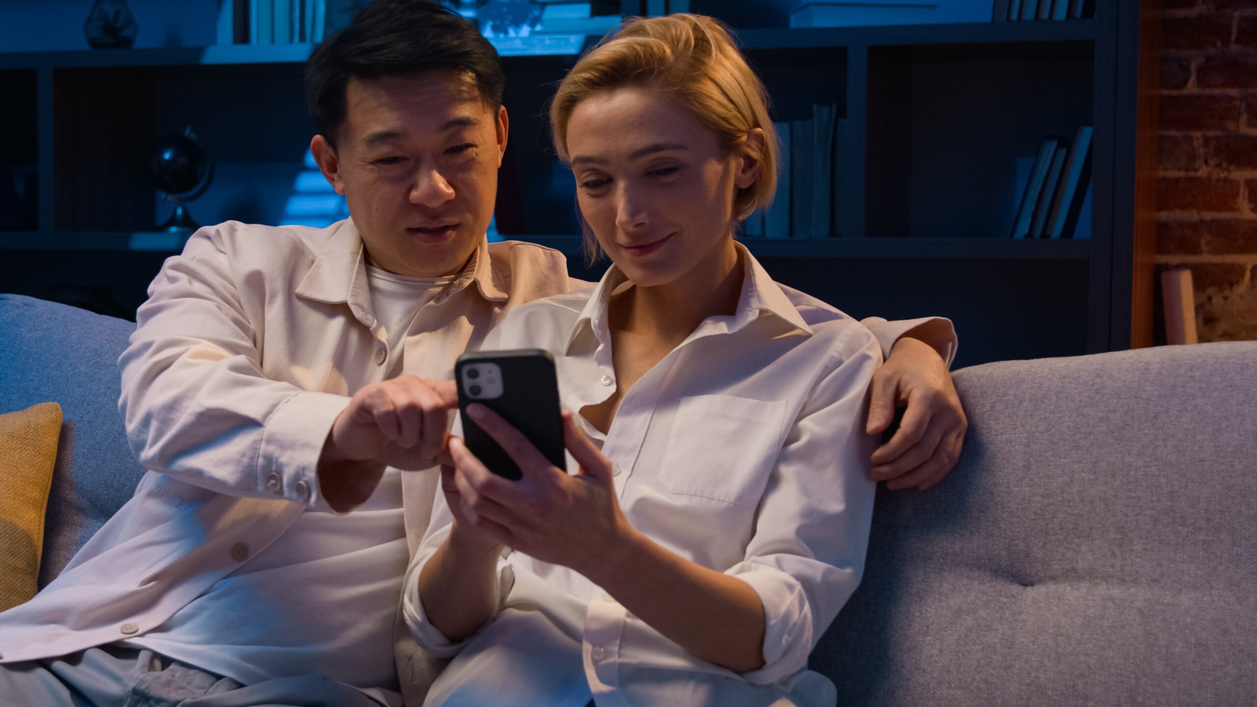 family-multiracial-couple-asian-man-caucasian-woman-night-home-buying-goods-internet-store-mobile-phone-shopping-online-with-smartphone-browsing-together-talking-discuss-order-food-delivery-min